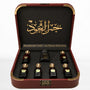 Al Mayas Selection Box: Open burgundy leather box with six perfume bottles, one dokhoon jar and gold corner details